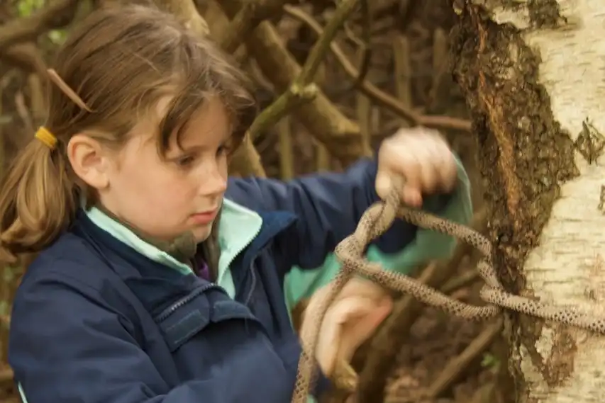 Young girl tying knots on a tree