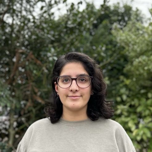 Halimah standing in front of a hedge