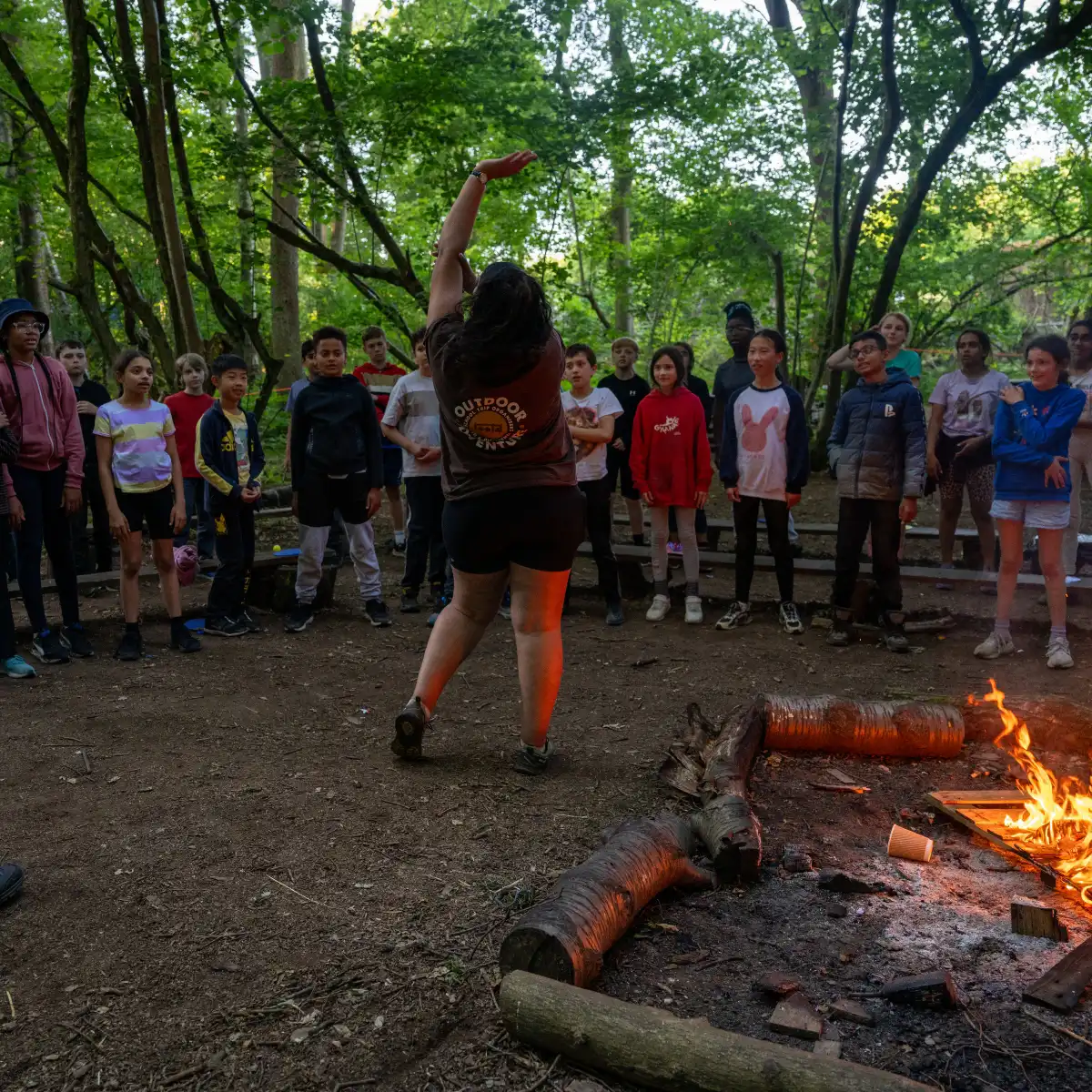 Rootd instructor leading evening games around the campfire